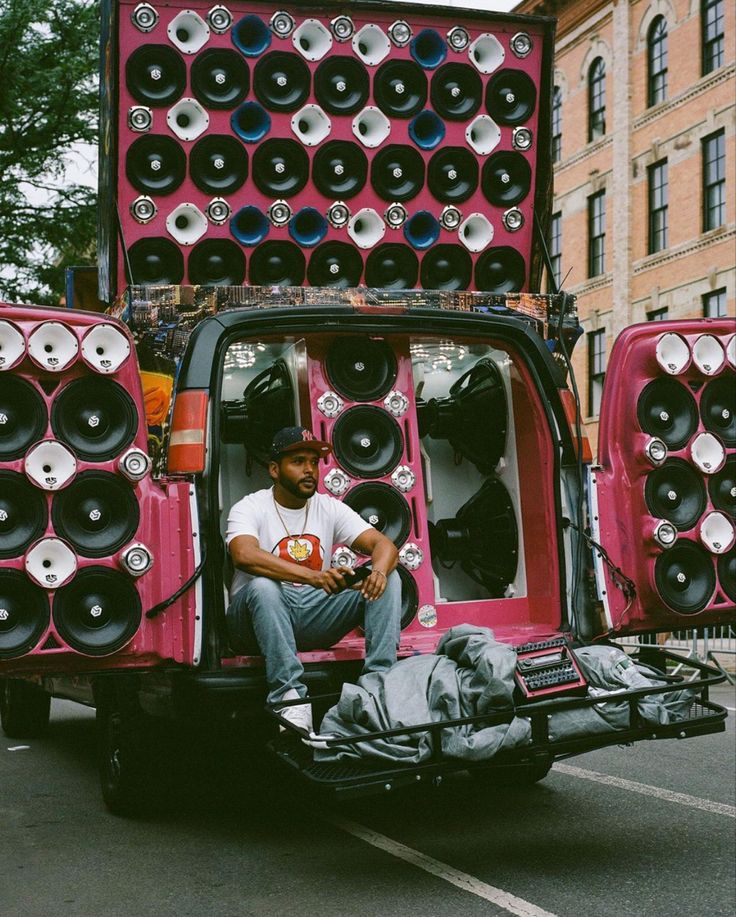 a man sitting in the back of a truck with speakers on it's bed