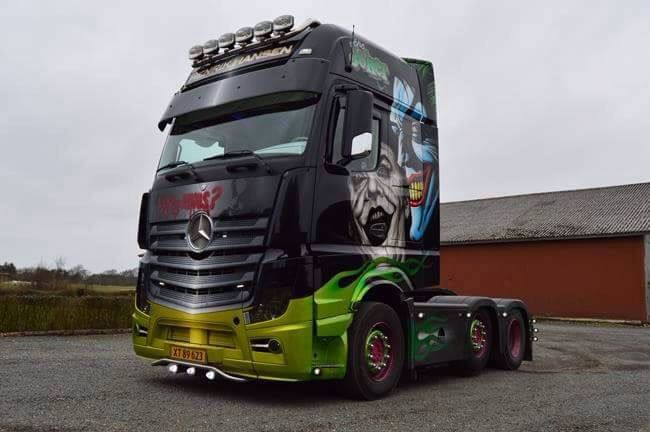 a green and black semi truck parked next to a building