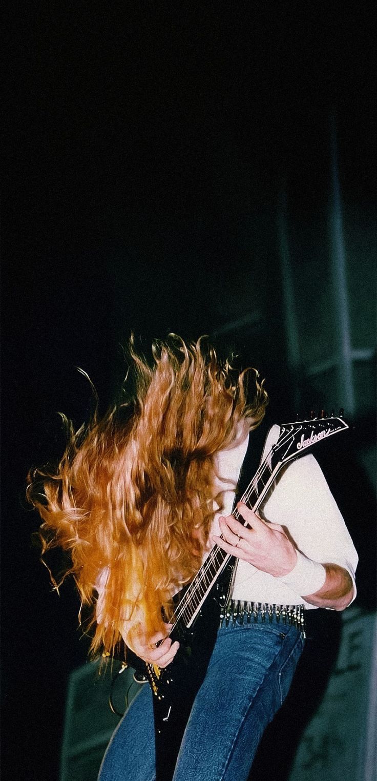 a woman with red hair playing an electric guitar