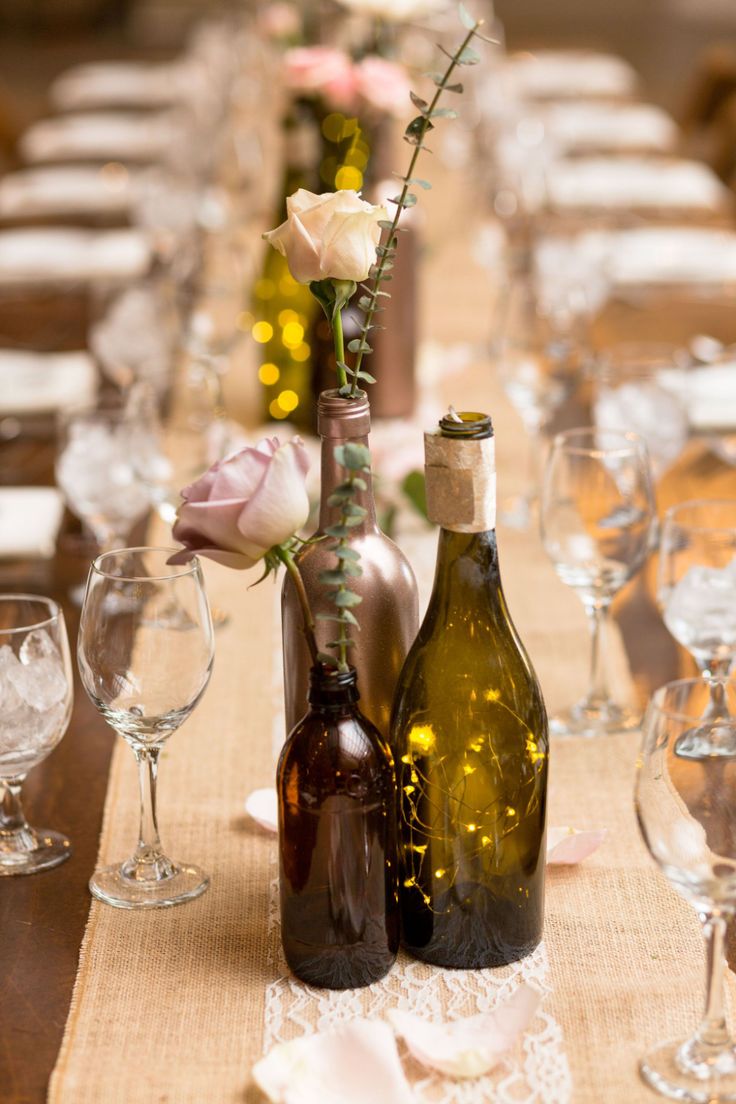 two wine bottles are sitting next to each other on a table with flowers in them