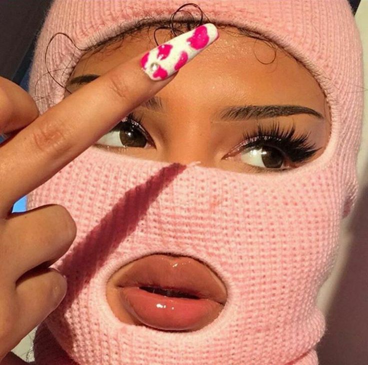 a woman wearing a pink knitted hat and holding her finger up to her nose