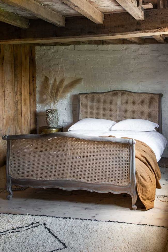 a bed with white sheets and pillows in a rustic style bedroom, next to an old brick wall