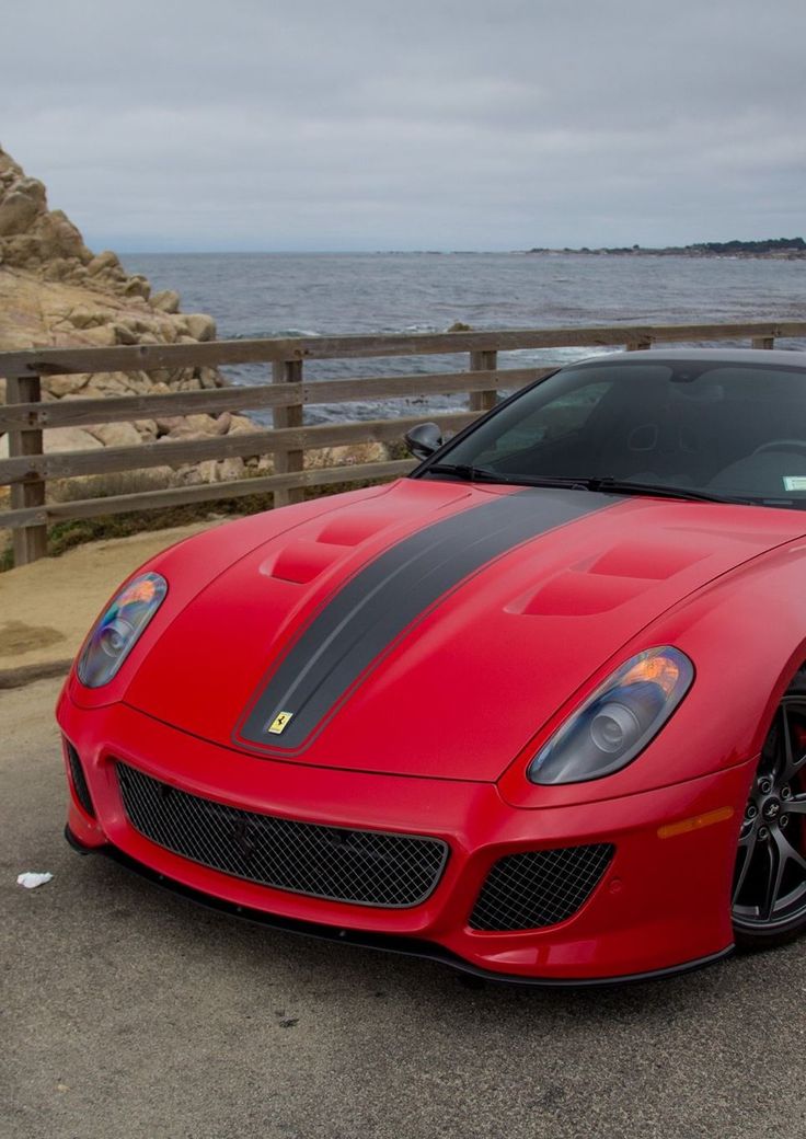 a red sports car parked next to the ocean