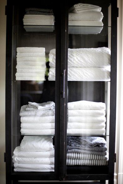 a glass cabinet with folded white towels in it