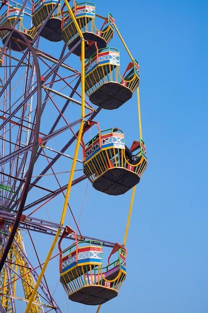 the ferris wheel is brightly colored and has four seats on each side, as well as several other rides