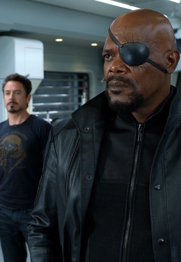 two men standing next to each other in front of a kitchen area with one man wearing an eye patch