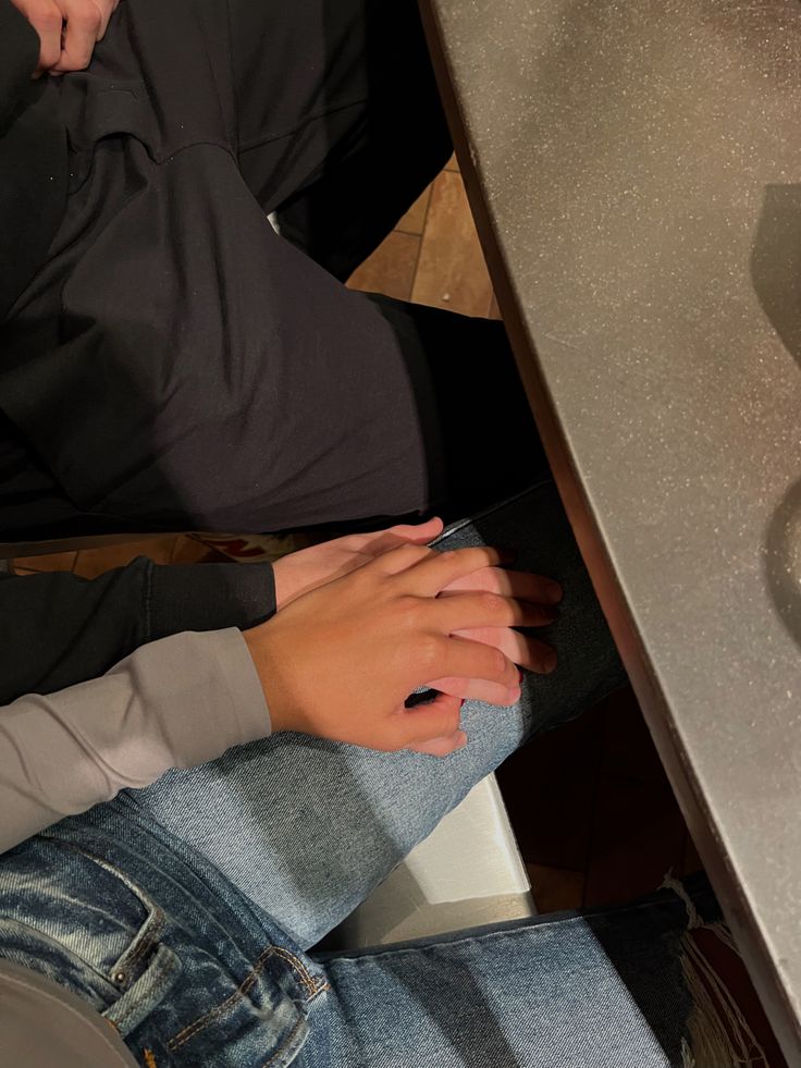 two people sitting at a table with their hands on each other's legs,