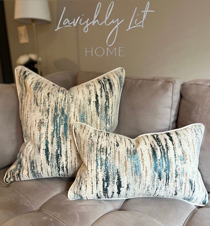 two pillows sitting on top of a couch in front of a wall with the words happily lit home