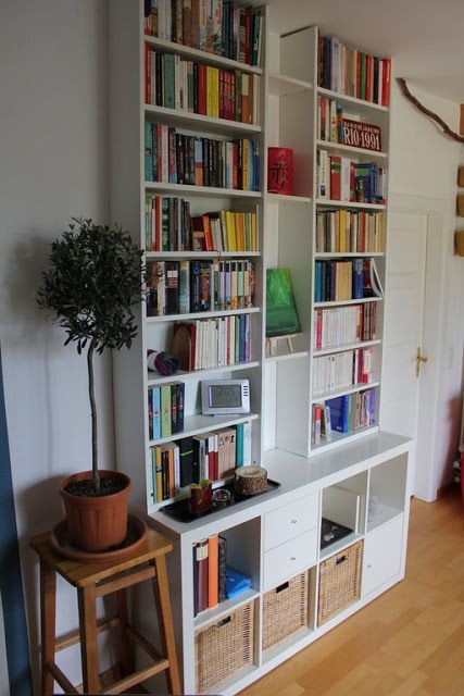 a bookshelf filled with lots of books next to a potted plant