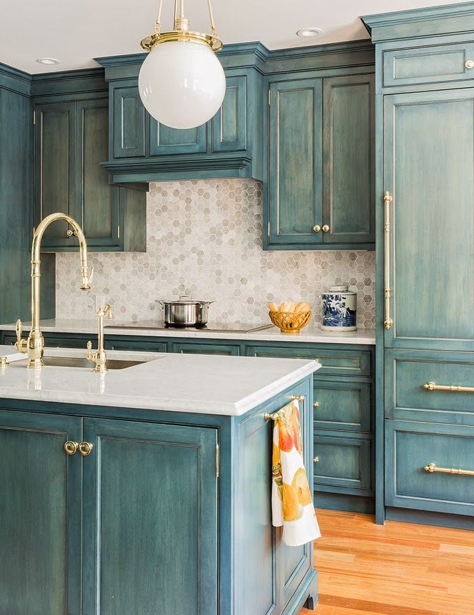 a kitchen with blue cabinets and white counter tops, gold faucet lighting over the sink