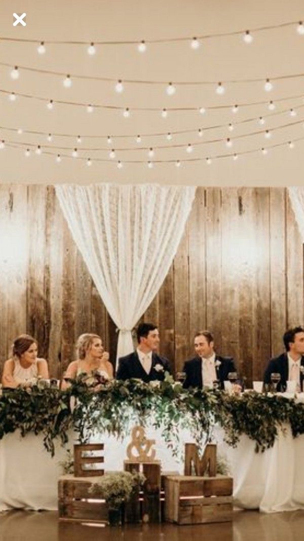 a group of people sitting at a table in front of a wooden wall with lights