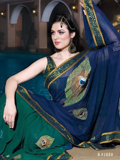 a woman in a peacock print sari sitting next to a pool