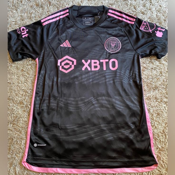 a black and pink soccer jersey laying on the floor