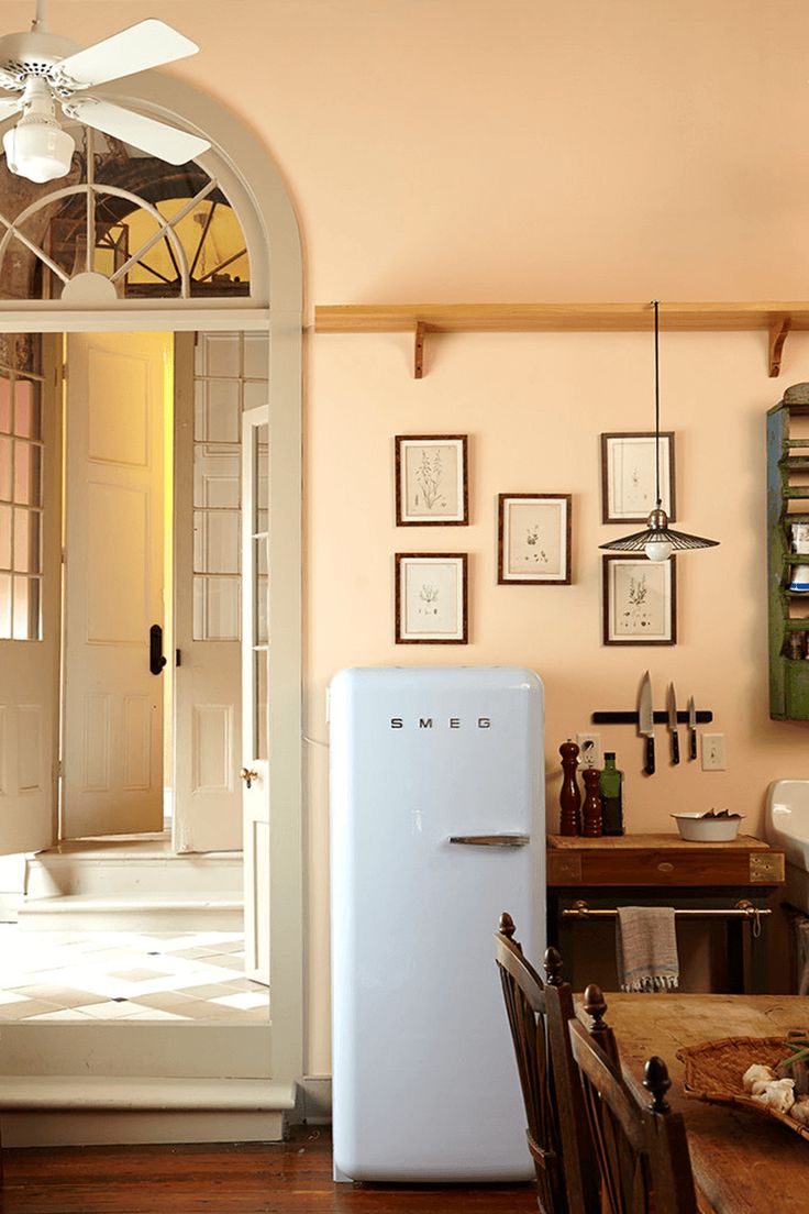 a white refrigerator freezer sitting inside of a kitchen next to a table and chairs