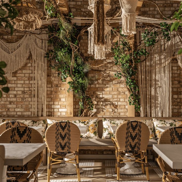 a restaurant with wicker chairs and plants on the wall behind them, surrounded by greenery