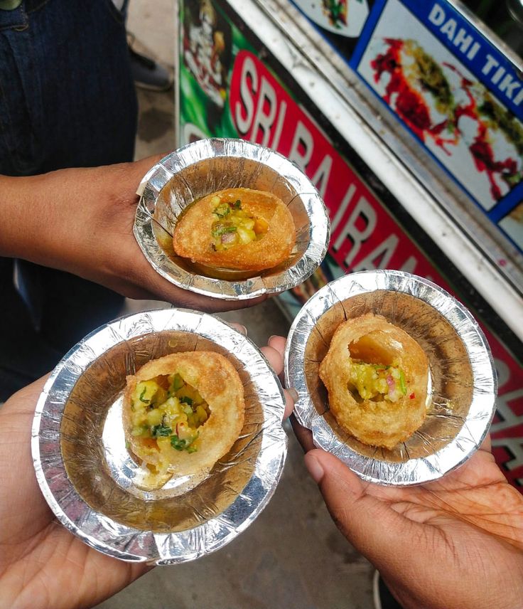 three people holding silver foil plates with food in them