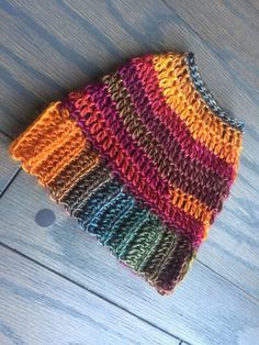 a multicolored knitted beanie sitting on top of a wooden floor