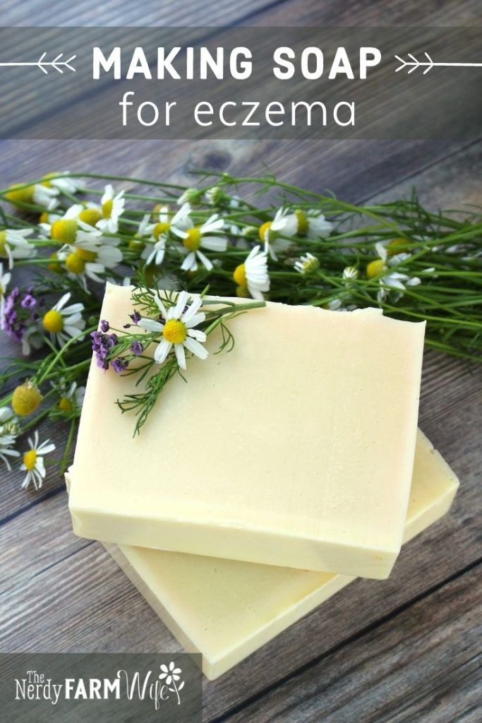 two bars of soap sitting on top of each other with daisies in the background