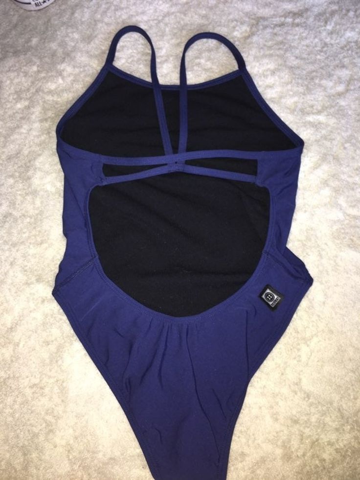 a woman's blue and black one piece swimsuit laying on top of a white carpet