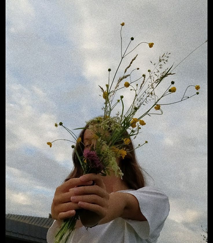 a woman holding flowers up to her face