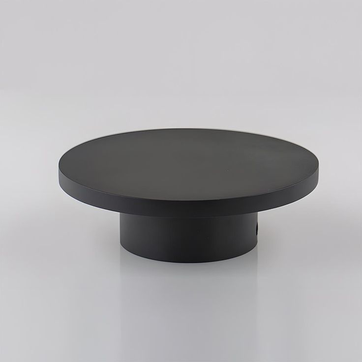 a black round table on a white surface with no one around it or someone else