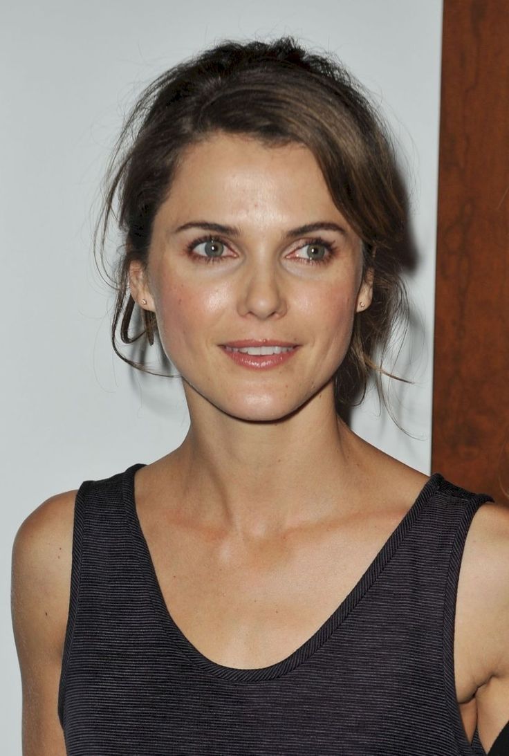 a close up of a person wearing a tank top and smiling at the camera with her hair pulled back