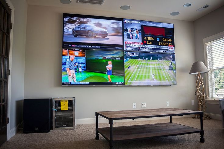 a large television mounted to the side of a wall next to a wooden coffee table