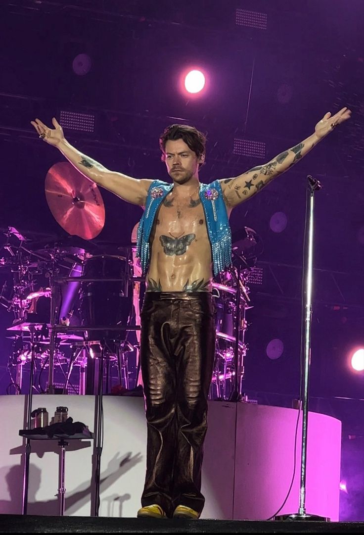 a shirtless man standing on stage with his arms spread out in front of him