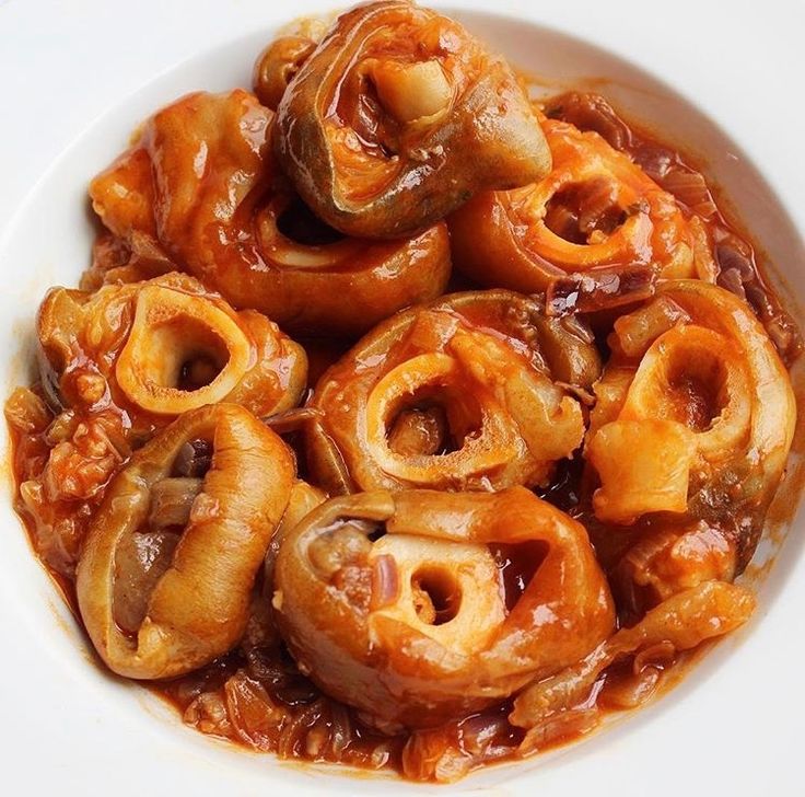 a white bowl filled with onion rings covered in sauce