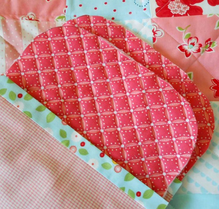 the quilts are all different colors and patterns on the table cloth, but one is pink