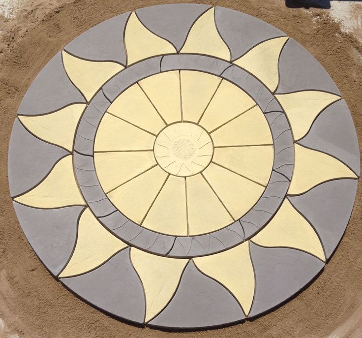 a sunflower design on the side of a building with sand in front of it