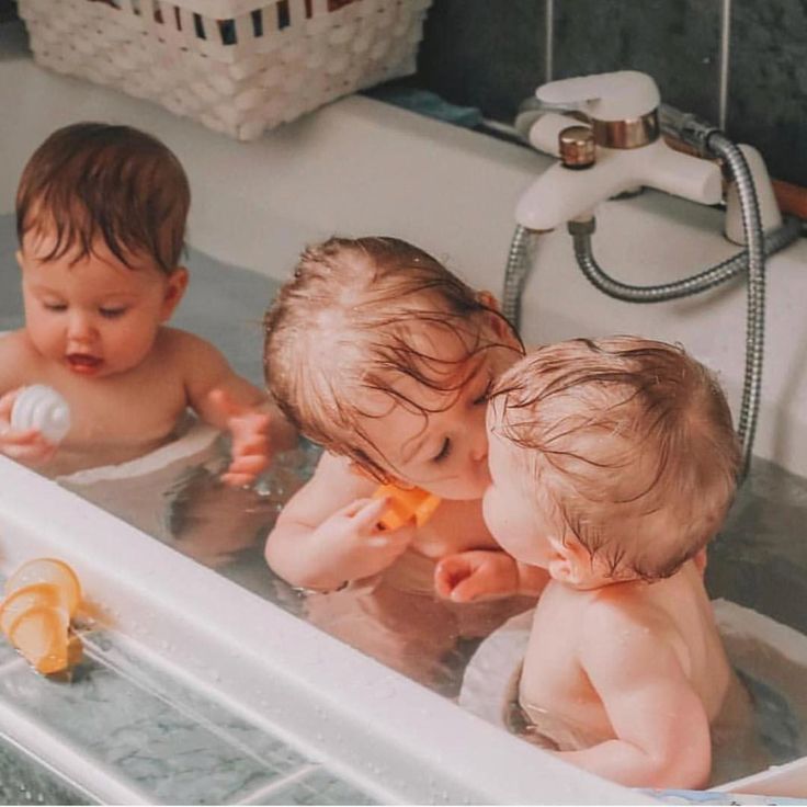 three babies are playing in the bathtub together