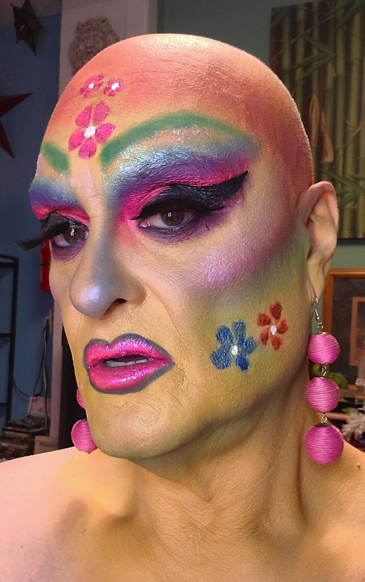 a woman with colorful makeup and flower decorations on her face is looking at the camera