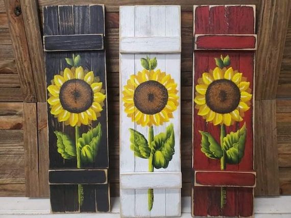 three sunflowers painted on wooden planks are shown