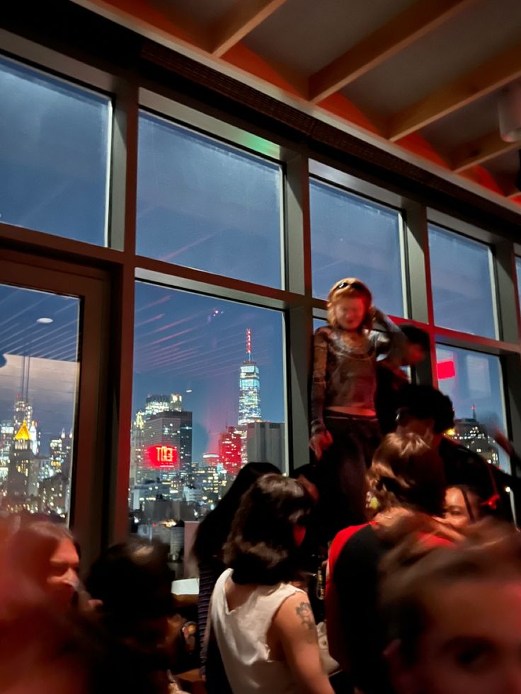 a young boy standing on top of a window sill in front of a cityscape