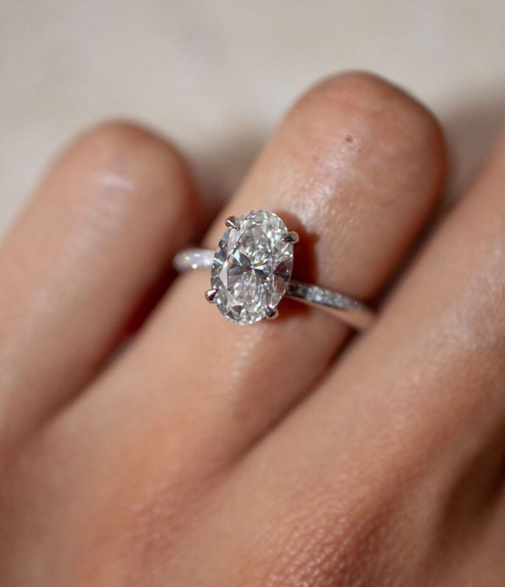 a woman's hand with a diamond ring on top of her finger, showing the center stone