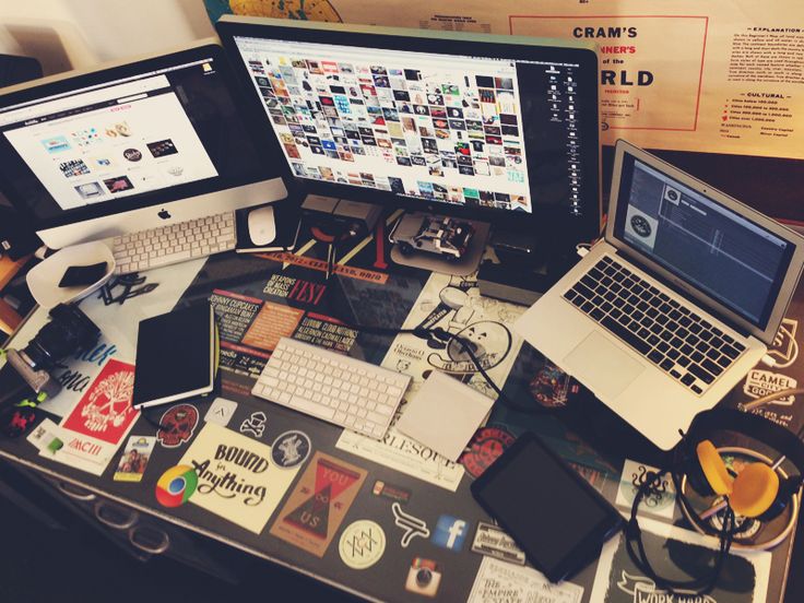 two laptops are sitting on top of a desk with various stickers all over it