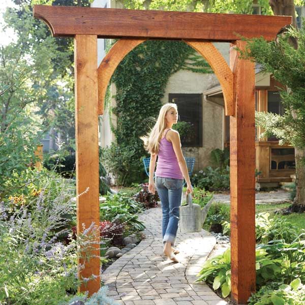 a woman walking through a garden with lots of plants