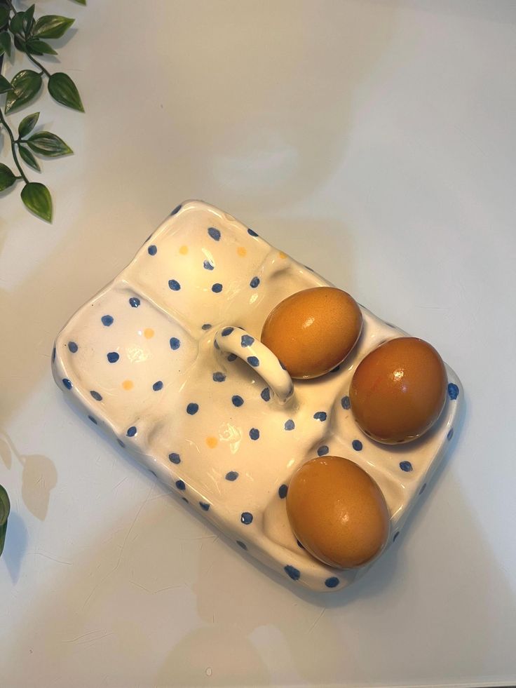 three brown eggs in a ceramic tray with polka dots