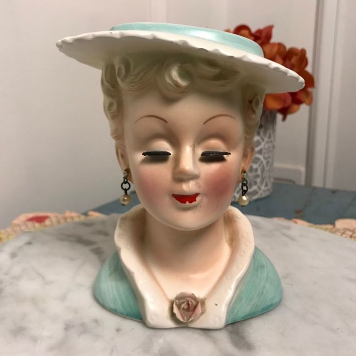 a ceramic statue of a woman wearing a hat on top of a table