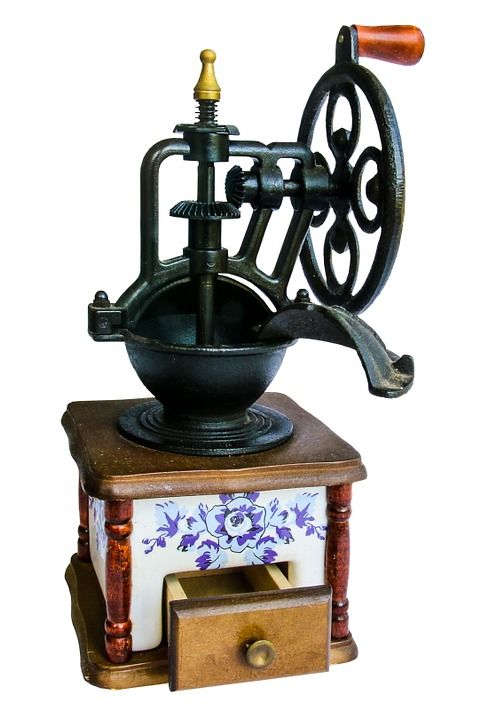 an old fashioned coffee grinder sitting on top of a wooden table next to a drawer