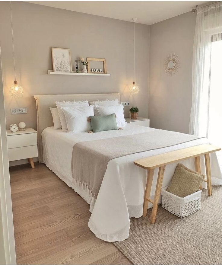 a white bed sitting in a bedroom next to a wooden table and window sill