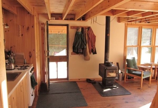 an open kitchen and living room area with wood flooring, stove top oven and chairs