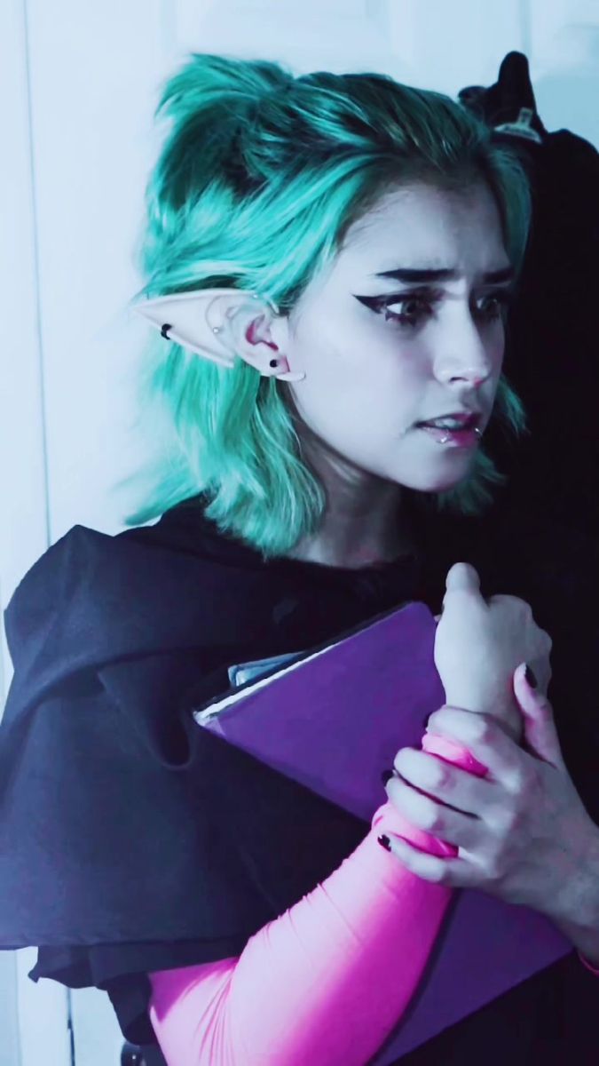 a woman with green hair is holding a folder and looking at something in her hand