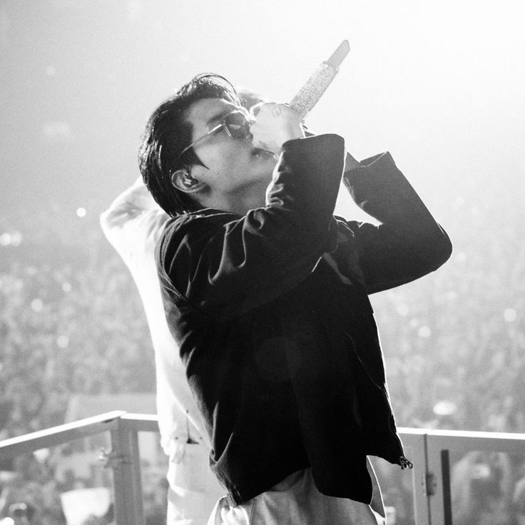 a black and white photo of a man drinking from a bottle in front of an audience