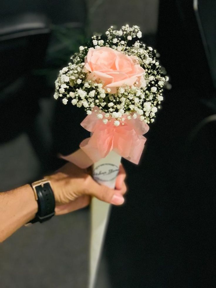 a person holding a bouquet of flowers in their left hand and the other hand with a tag on it