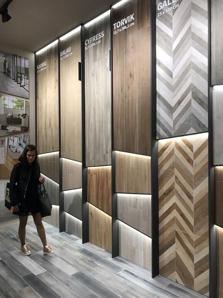 a woman is walking through a store with wood panels on the walls and flooring