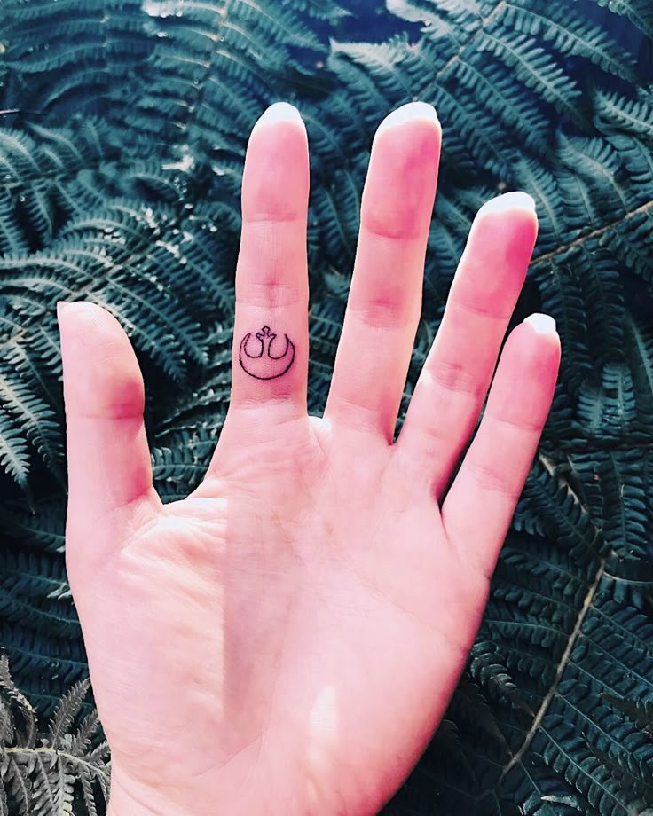 a person's hand with a small crown tattoo on it