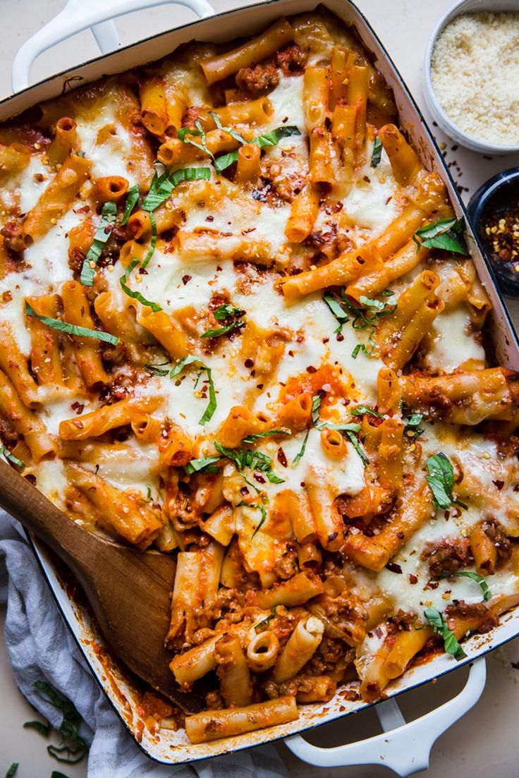 a casserole dish filled with pasta and meat, topped with parmesan cheese