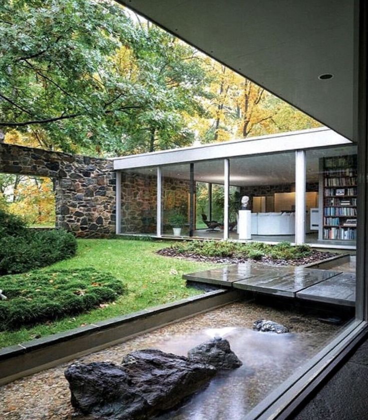 the interior of a modern house with stone walls and floor to ceiling windows overlooking a garden